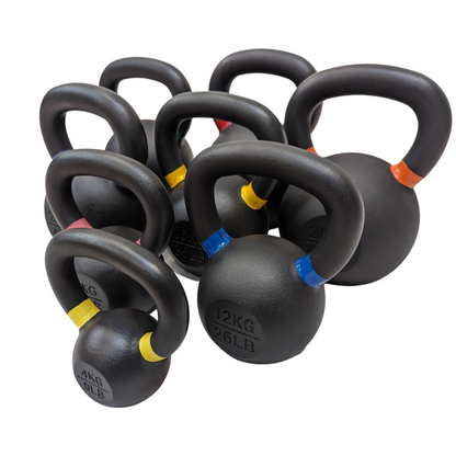 Set of black cast iron kettlebells with powder-coated handles, each marked by colored bands and weight labels ranging from.